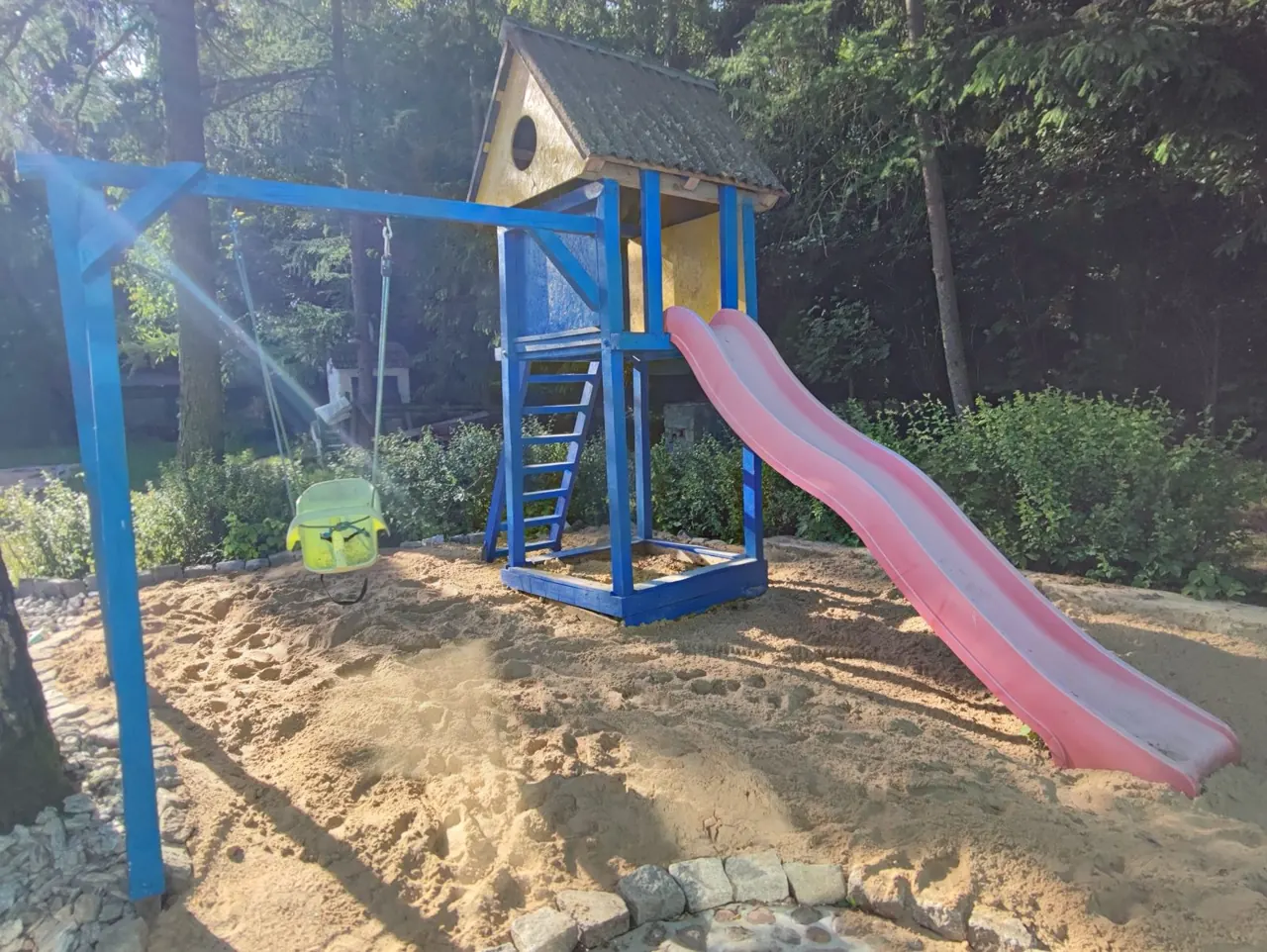 Plac zabaw z domkiem, zjeżdżalnią i huśtawką w piaskownicy