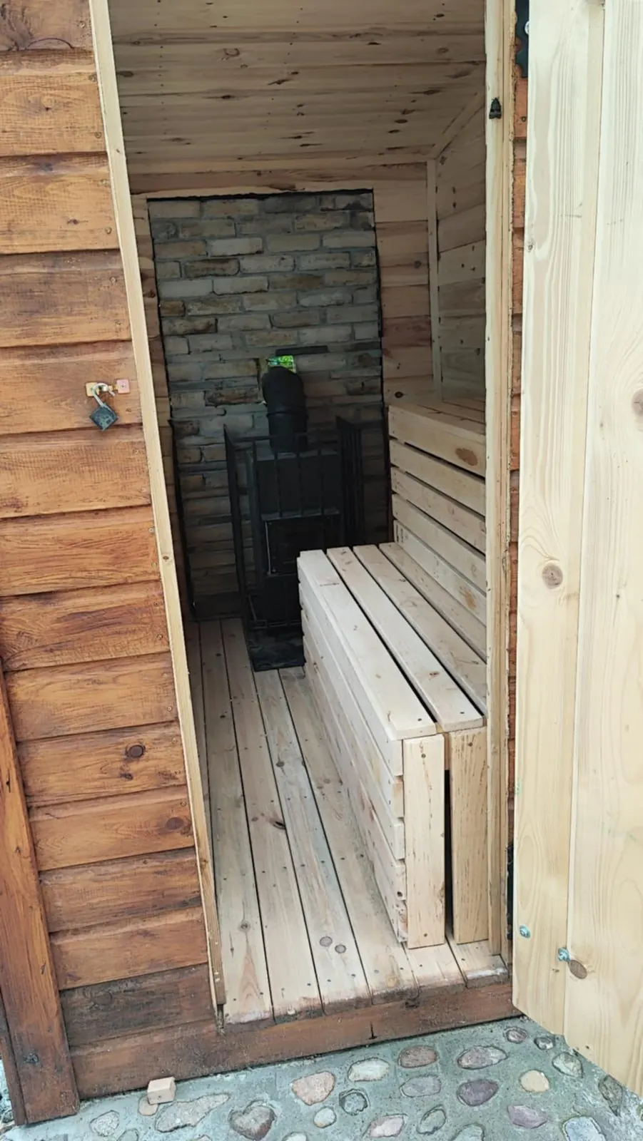Sauna widziana od wejścia, z piecem i drewnianymi ławami